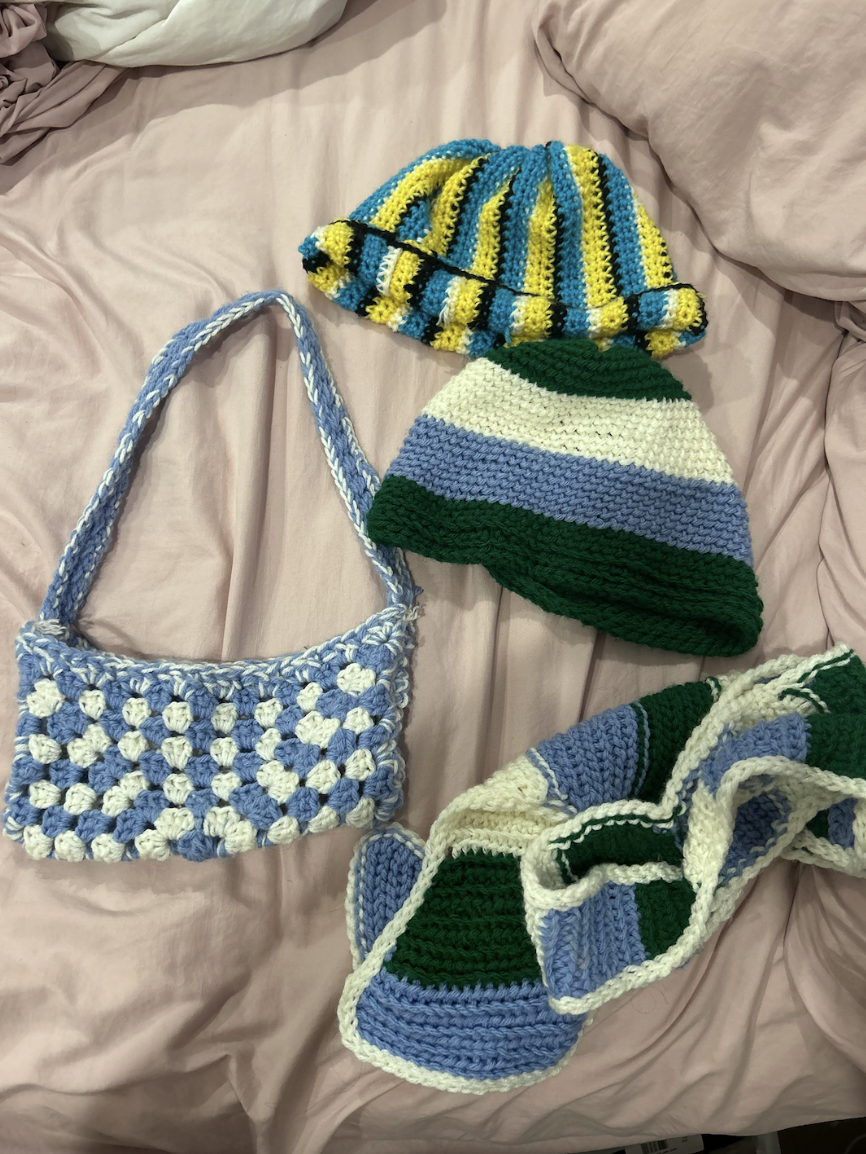 Senior Everett Smith shows their crocheted scarf, bag, and beanies.